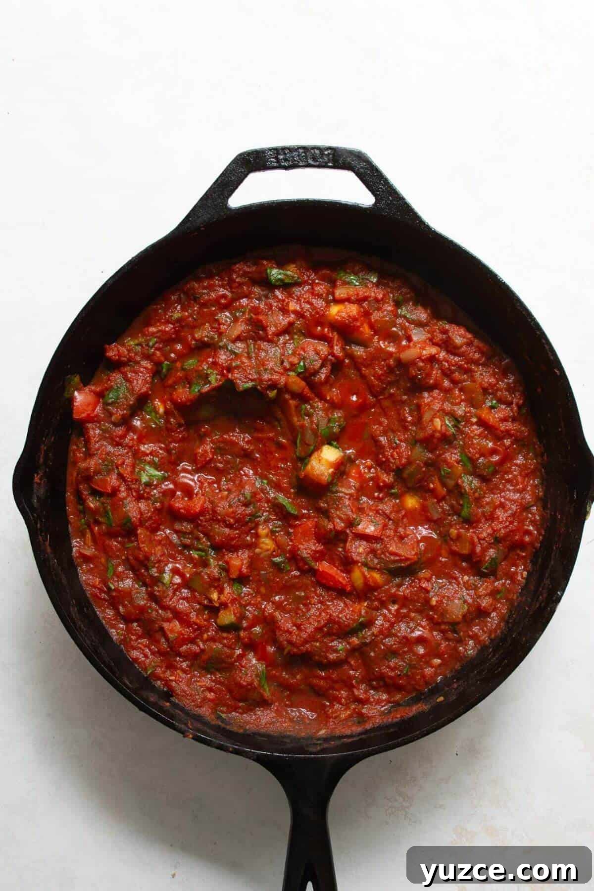 Perfect Shakshuka Recipe: Flavorful One-Pan Eggs and Tomatoes 6 Adding canned crushed tomatoes to a cast iron pan with peppers and onions