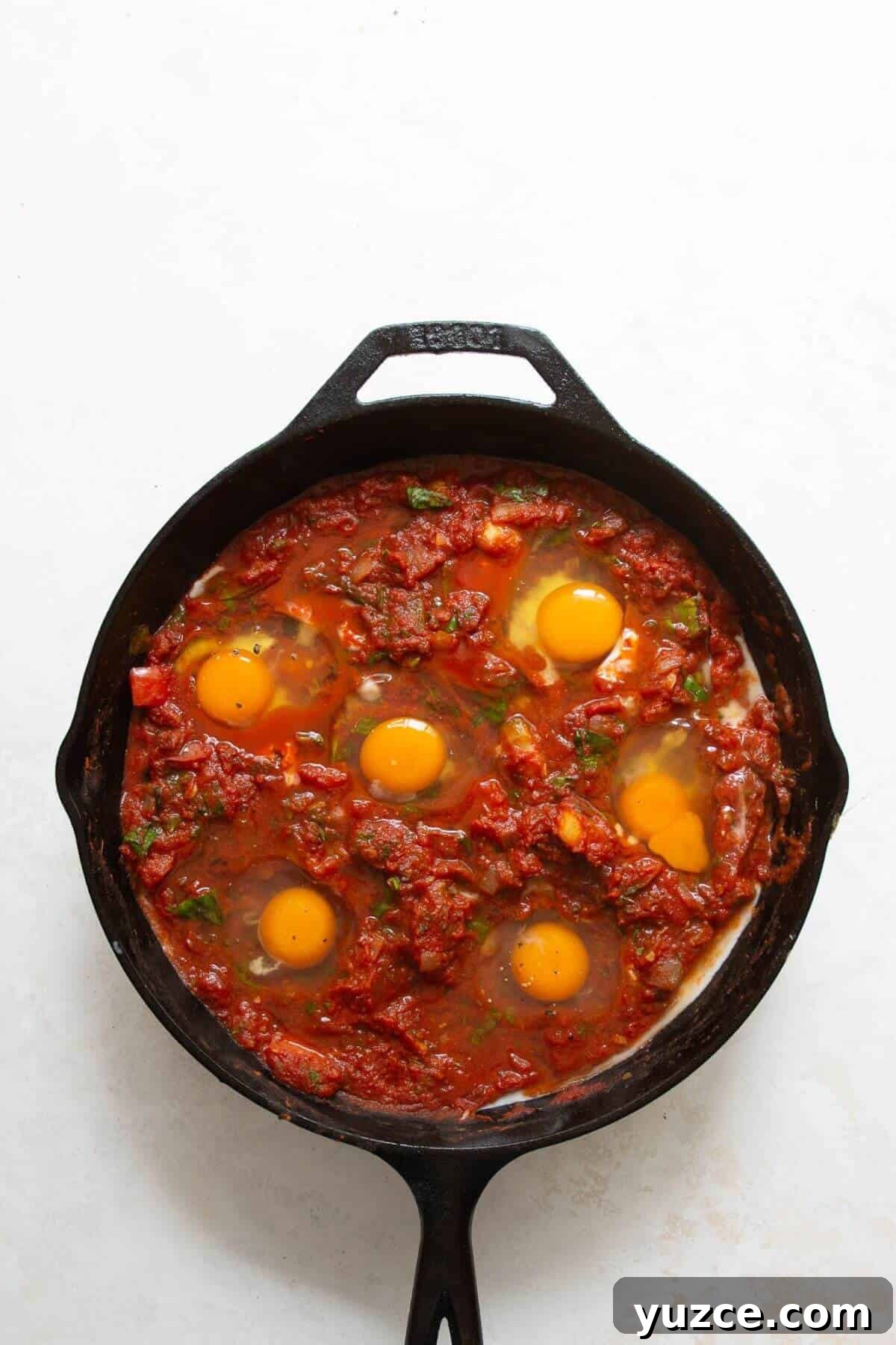 Perfect Shakshuka Recipe: Flavorful One-Pan Eggs and Tomatoes 7 Cracking eggs into wells in the tomato sauce for shakshuka