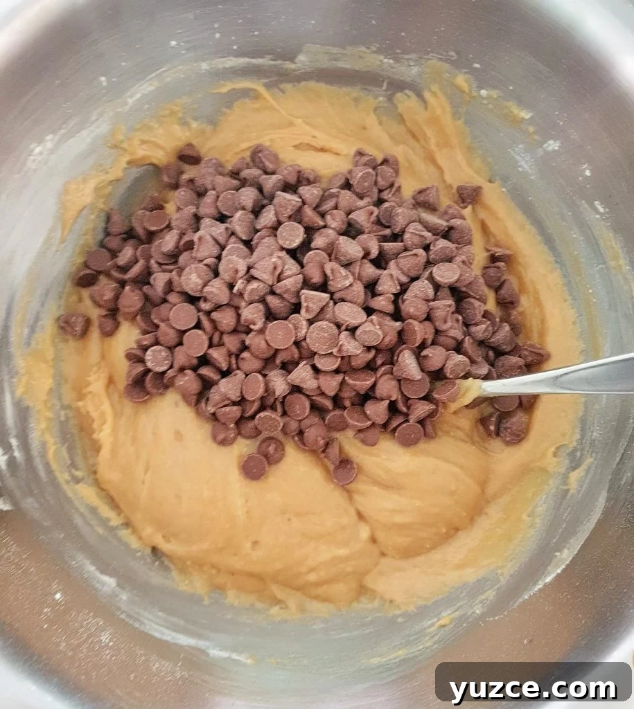 Salted Caramel Cookie Pie Recipe: Gooey, Crunchy Dessert Guide 9 Chocolate chips added to cookie dough in a bowl.