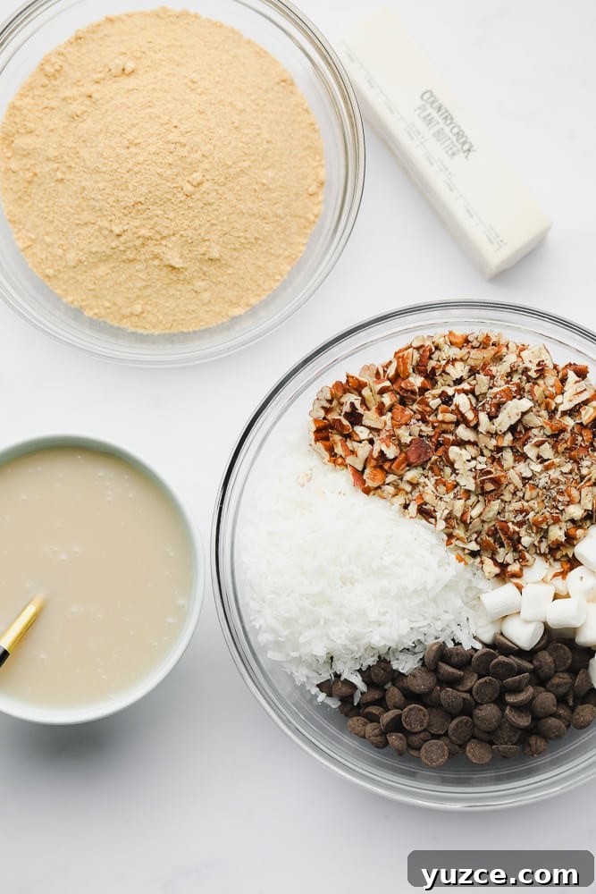 3 bowls filled with crushed graham crackers, nuts, chocolate, and coconut, and condensed milk.