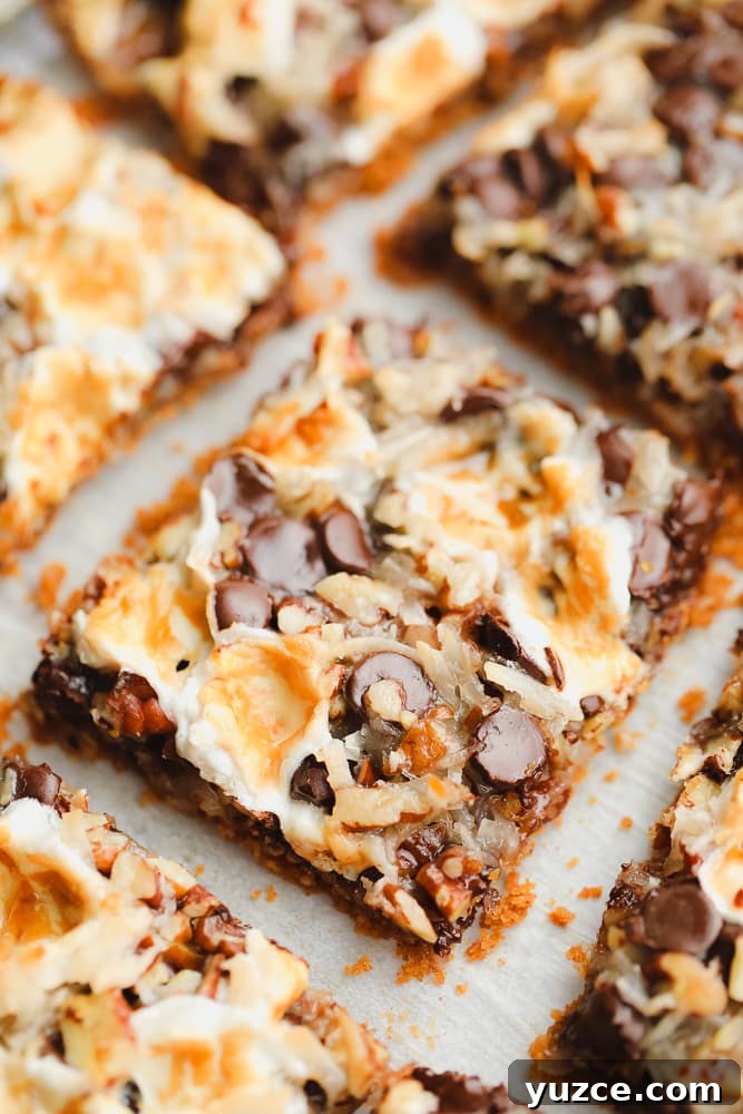 close up on a cut cookie bar with toasted marshmallows, coconut, and chocolate on top.