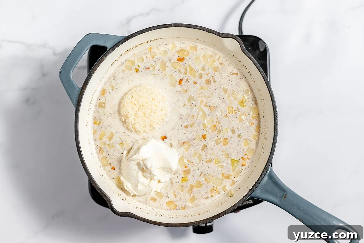 Creamy Loaded Baked Potato Soup Recipe 6 Cream cheese and Parmesan cheese are added to the onion and milk mixture in the skillet.