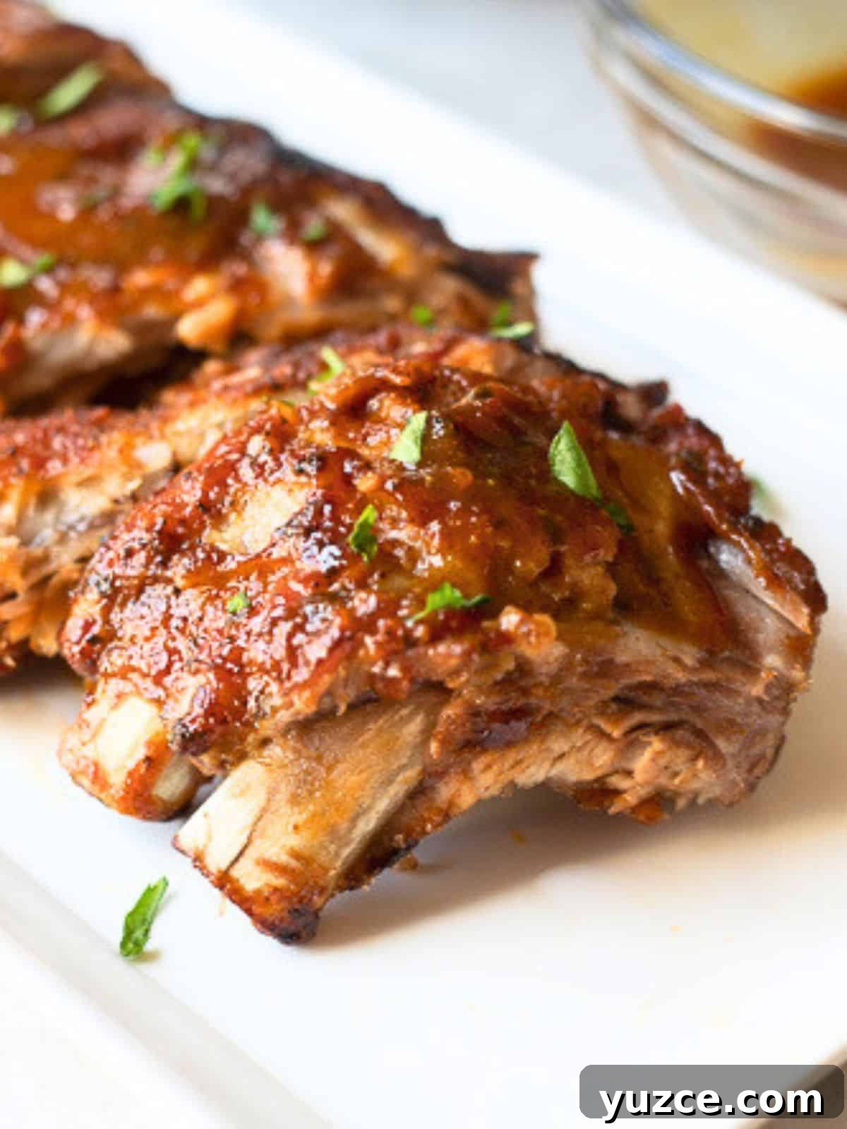 Instant Pot Ribs Instant Pot Ribs on white platter next to Instant Pot after being brushed with BBQ sauce and broiled.