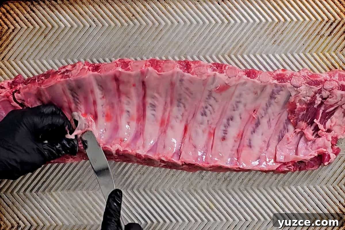 Instant Pot BBQ Ribs Butter knife sliding under ribs to remove membrane under ribs.
