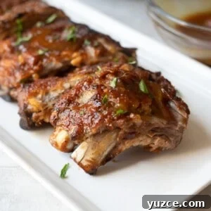 Tender Instant Pot Ribs: Quick Pressure Cooker Recipe for Fall-Off-the-Bone Results 3 Instant Pot Ribs on platter topped with BBQ sauce.