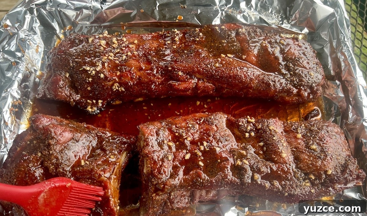 Hot Maple glazed ribs. Ribs in foil with glaze brushing over.