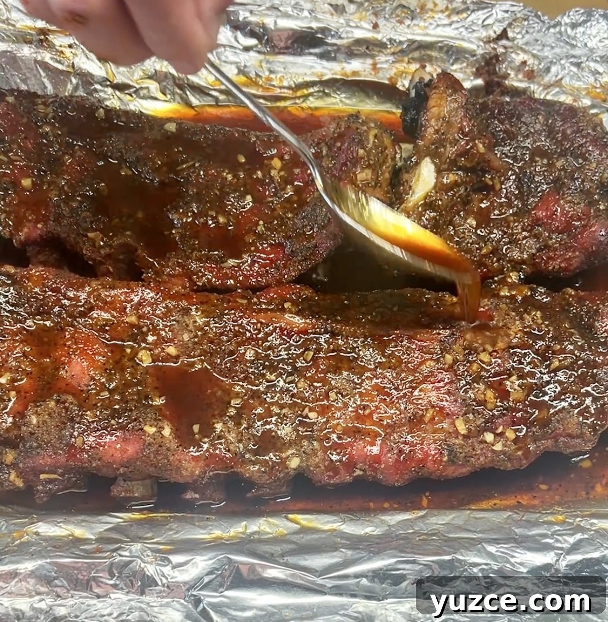 Spicy maple grilled pork ribs. Spooning glaze over grilled ribs.
