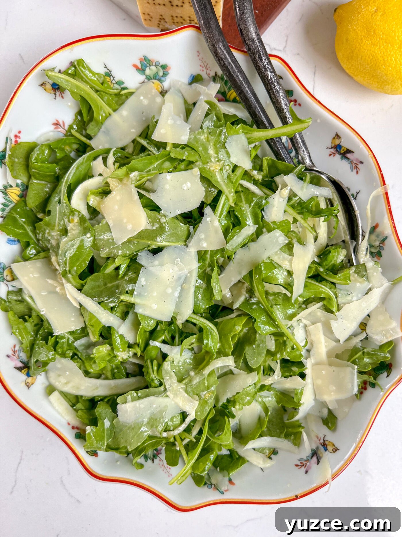 Arugula and Fennel Salad with Lemon-Parmesan Dressing 3 An arugula fennel salad with a delicious honey dijon dressing with a lemon on the side and fork in the plate.