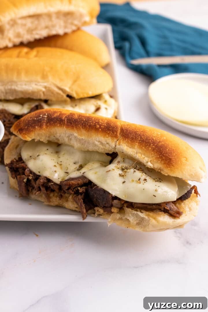 Slow-Cooker French Dip Sandwiches with Savory Au Jus 2 Slow Cooker French Dip sandwiches on a white serving plate.