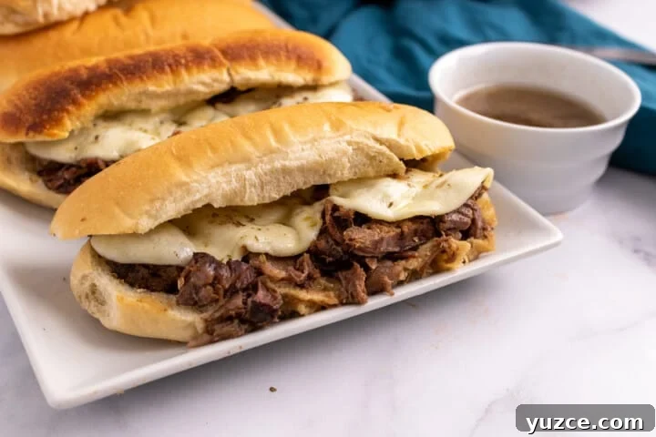 Slow-Cooker French Dip Sandwiches with Savory Au Jus 4 French Dip Sandwiches on white serving tray.