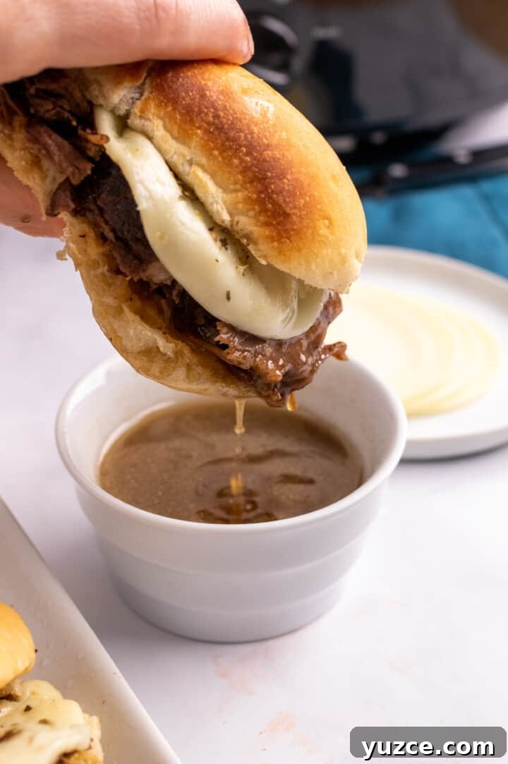 Slow-Cooker French Dip Sandwiches with Savory Au Jus 9 Dipping the French Dip sandwich into a cup of the au jus.