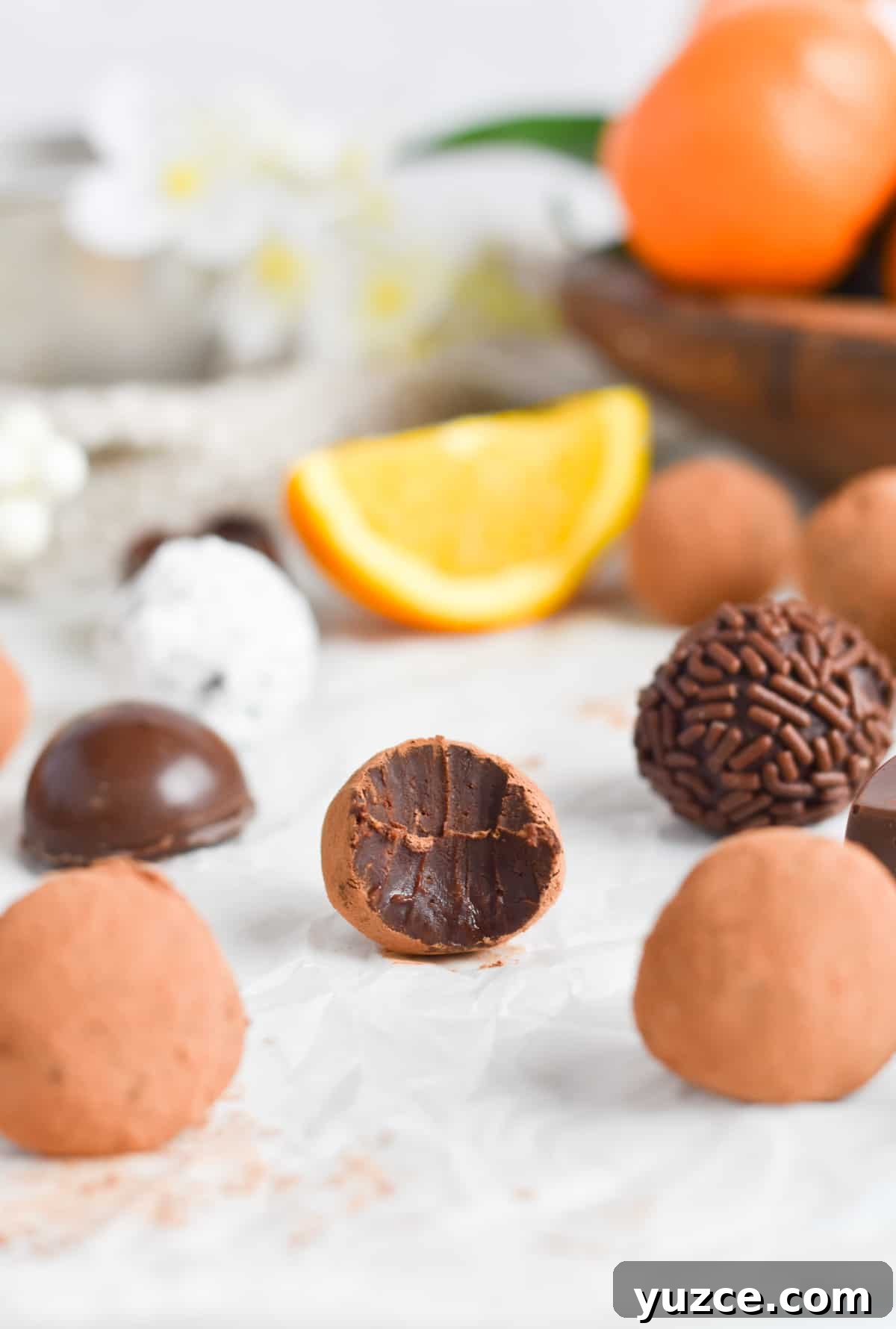 Decadent Chocolate Orange Truffle Recipe for Giftable Sweets 2 chocolate truffle with bite out of it on parchment paper.