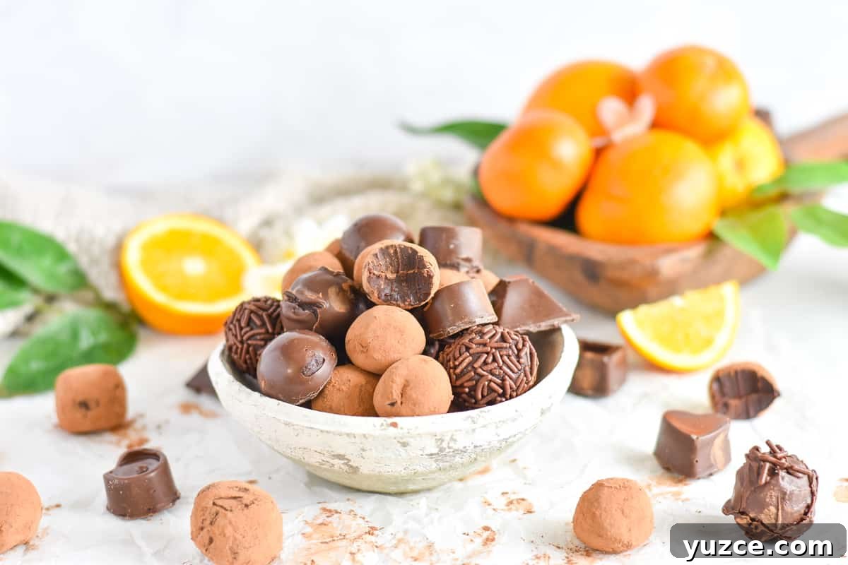 Decadent Chocolate Orange Truffle Recipe for Giftable Sweets 8 truffles piled in white bowl with oranges in background.