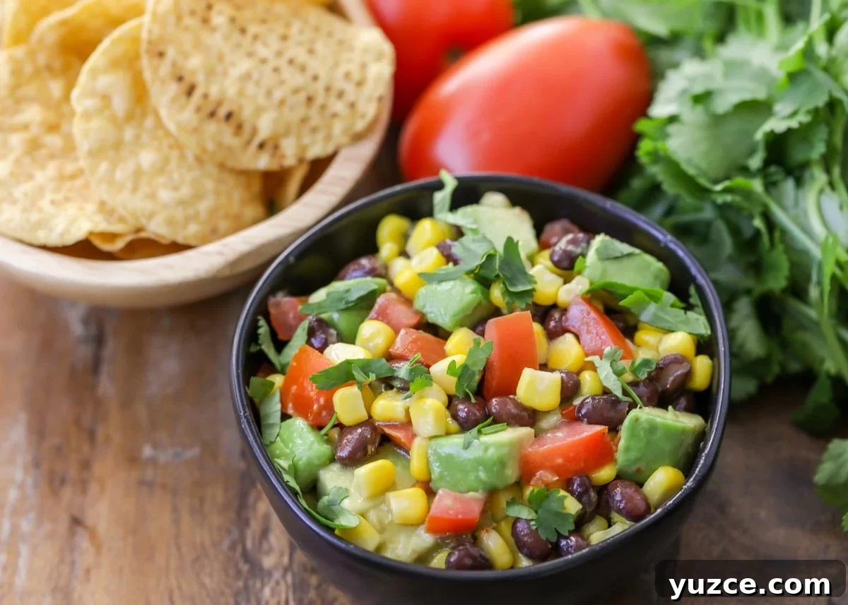 Fresh and chunky black bean corn salsa {aka Cowboy Caviar} is a favorite dip to serve with tortilla chips! Black Bean Corn Salsa served in a black bowl.