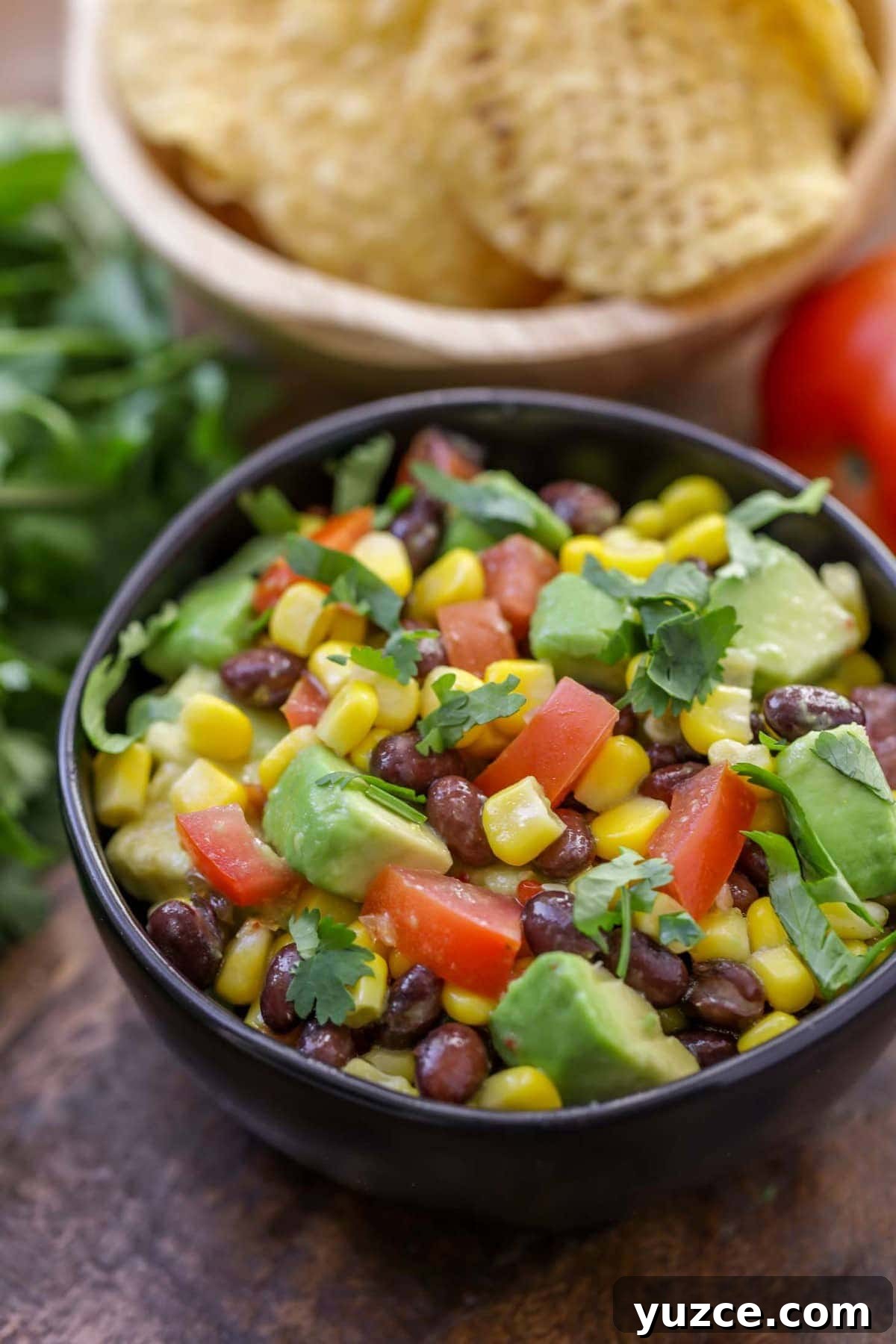 Fresh and chunky black bean corn salsa {aka Cowboy Caviar} is a favorite dip to serve with tortilla chips! Black Bean Corn Salsa Recipe in a black bowl close up image.