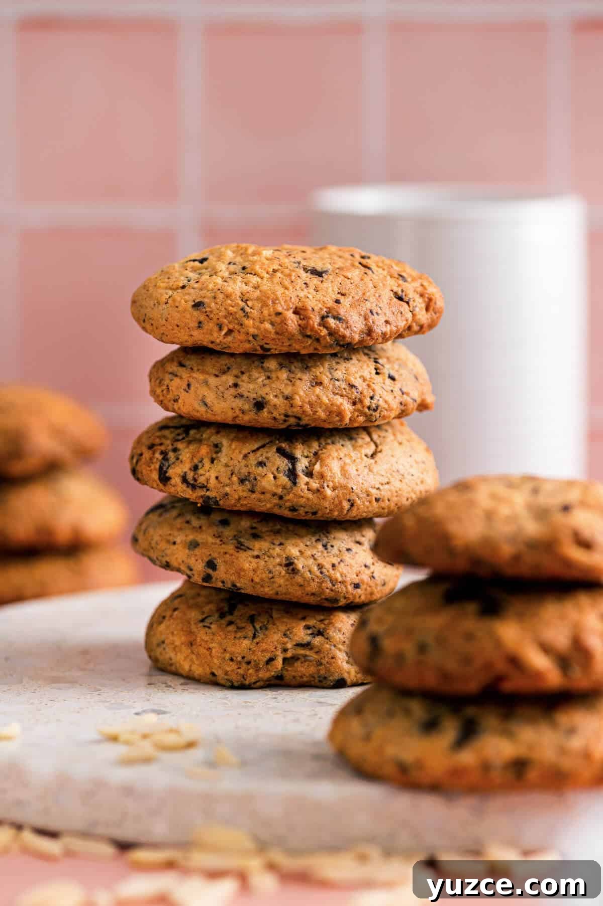 Chocolate Almond Cookie Recipe with Crunchy Almonds and Cocoa 2 Stacked chocolate almond cookies on a plate with extra cookies blurred in the background and slivered almonds scattered nearby.