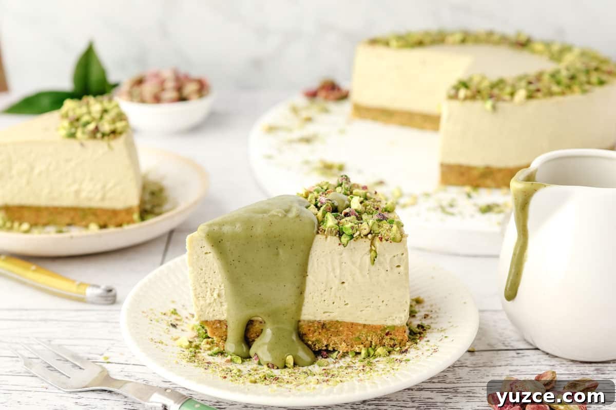 Crunchy Pistachio Topping Recipe for Desserts and Baked Goods 5 Slice of pistachio cheesecake on a plate with pistachio topping, with jar of sauce, another slice of cheesecake and rest of cut cheesecake in the background.