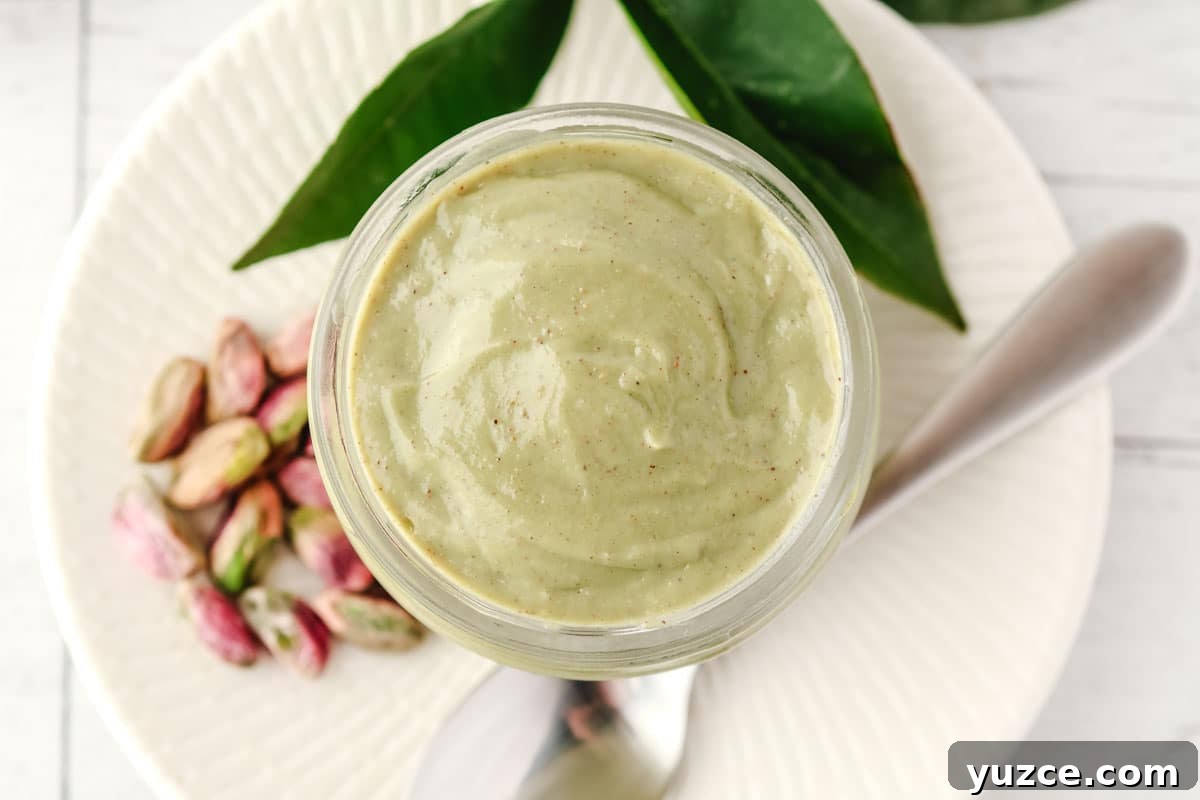 Crunchy Pistachio Topping Recipe for Desserts and Baked Goods 6 Top down shot of pistachio topping in a jar, with a spoon and pistachio nuts on the side.