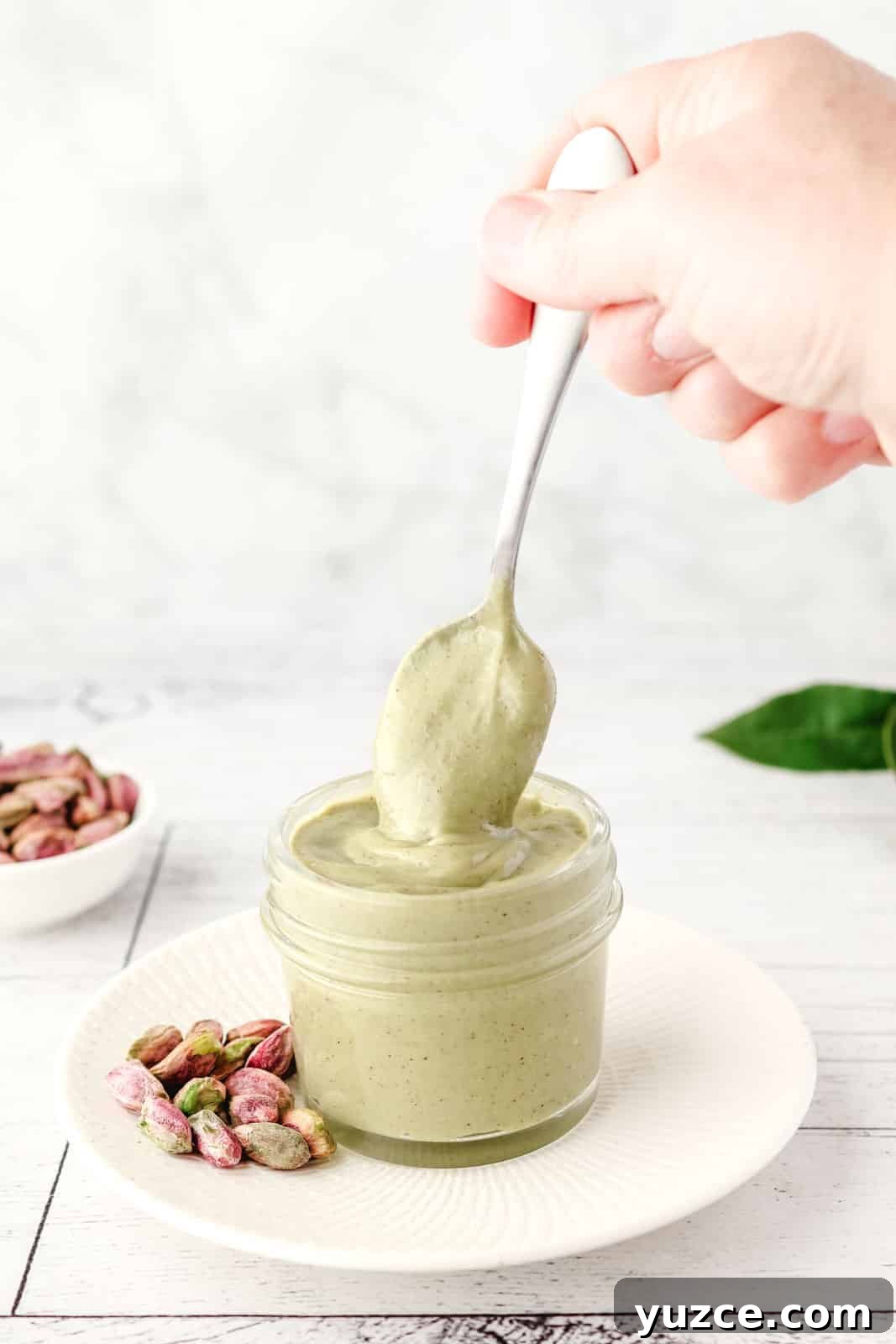 Crunchy Pistachio Topping Recipe for Desserts and Baked Goods 8 Spooning pistachio topping from a jar.