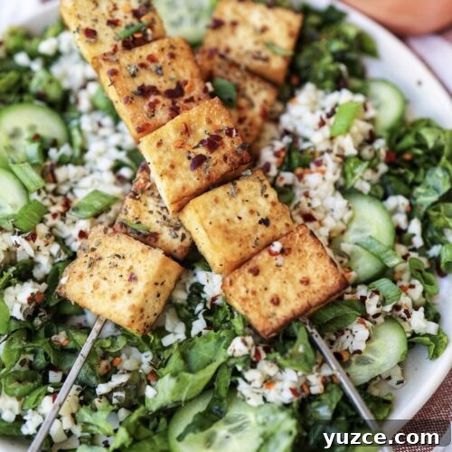 A salad topped with tofu satay and peanut sauce.