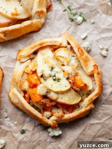 a gluten free savory galette with butternut squash, apples, sweet onions and blue cheese on brown parchment paper