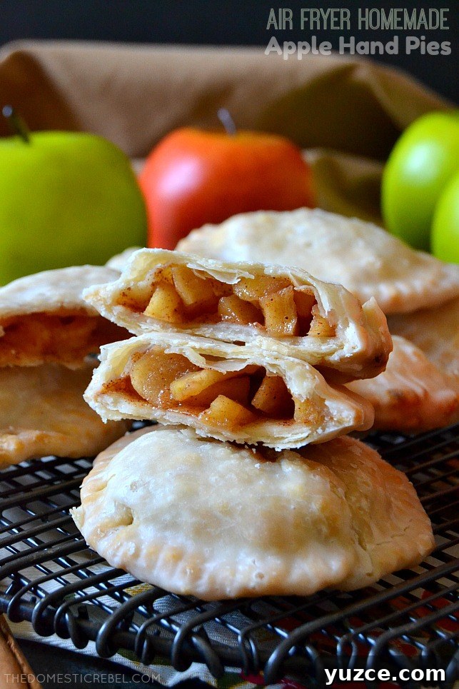 apple hand pies arranged on black wire rack with apples in background