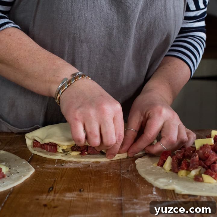 Authentic Cornish Pasty Recipe: Traditional Step-by-Step Guide 11 womans hands making three Cornish pasties on a wooden kitchen counter