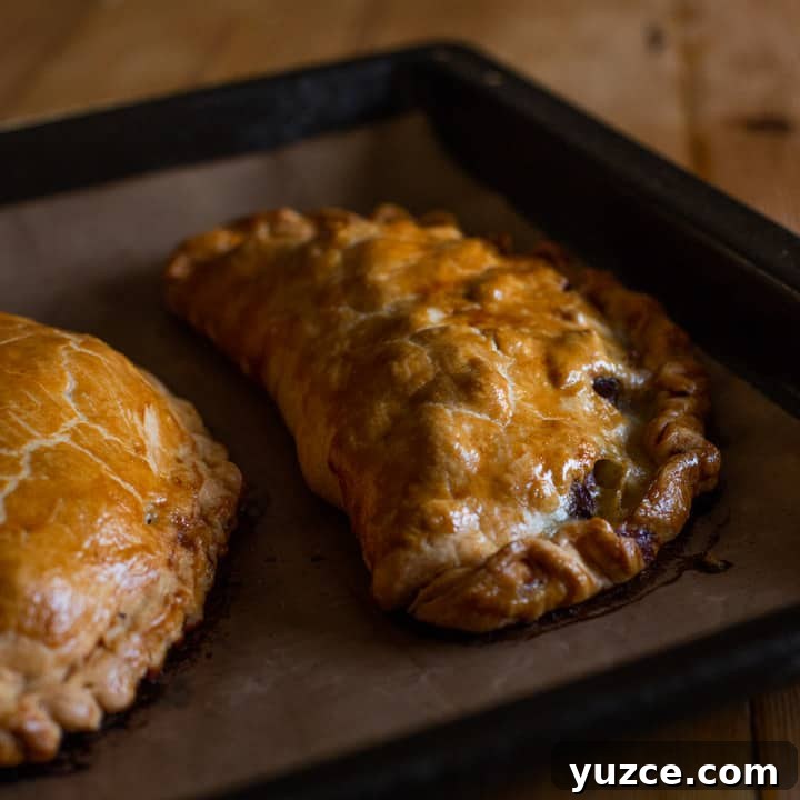Authentic Cornish Pasty Recipe: Traditional Step-by-Step Guide 15 golden brown baked pasty's on brown baking paper on a black tray