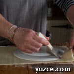 Authentic Cornish Pasty Recipe: Traditional Step-by-Step Guide 17 womans hands cutting pastry byt running a small knife round a white plate