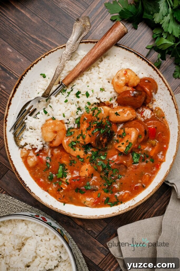 17 Delicious Gluten-Free Shrimp Recipes for Every Meal 18 Gluten-free gumbo on a white plate with a fork and spoon.