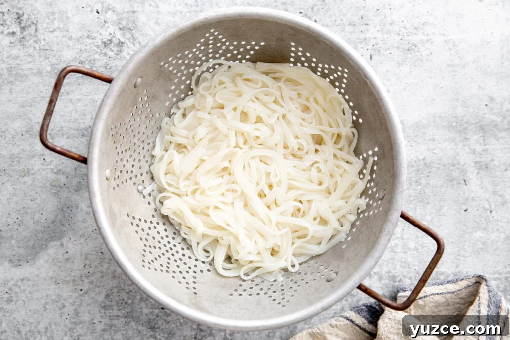 Spicy Peanut Pork Noodles (Gluten-Free, Ready in Minutes) 7 Cooked rice noodles in a colander.