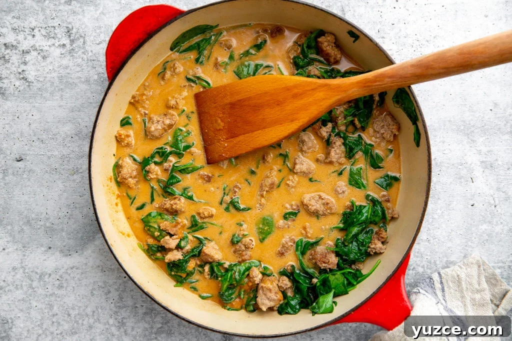 Spicy Peanut Pork Noodles (Gluten-Free, Ready in Minutes) 10 The pork and peanut sauce in a skillet with a wooden spoon.