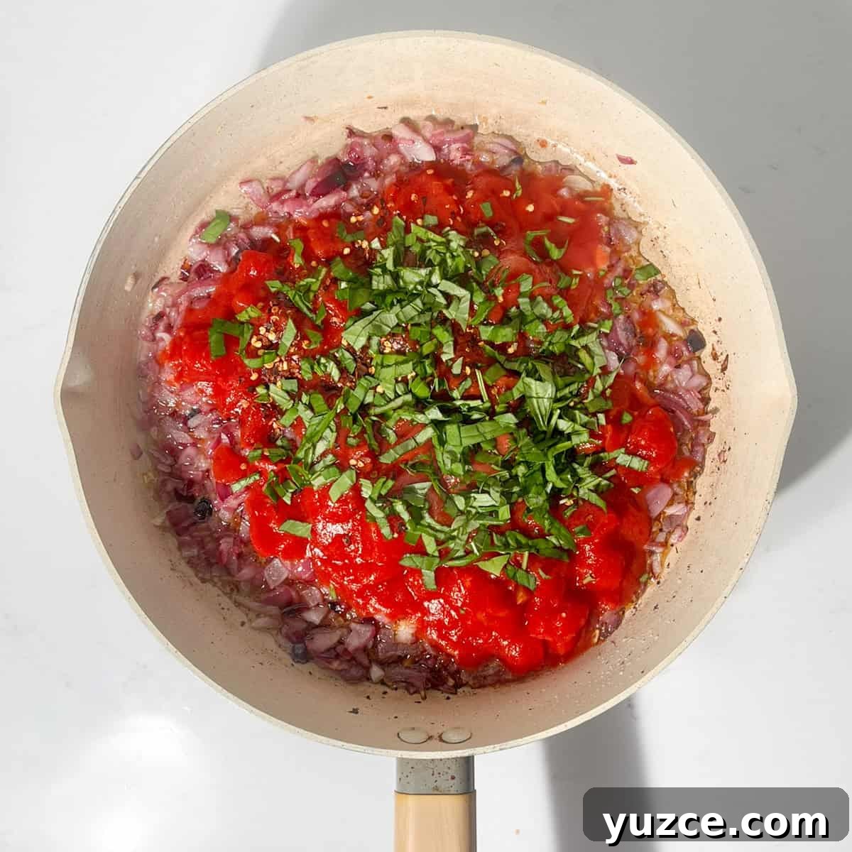 Spaghetti all’Arrabbiata Recipe: Spicy Tomato Pasta Guide 7 Adding basil to the sauce in the frying pan.