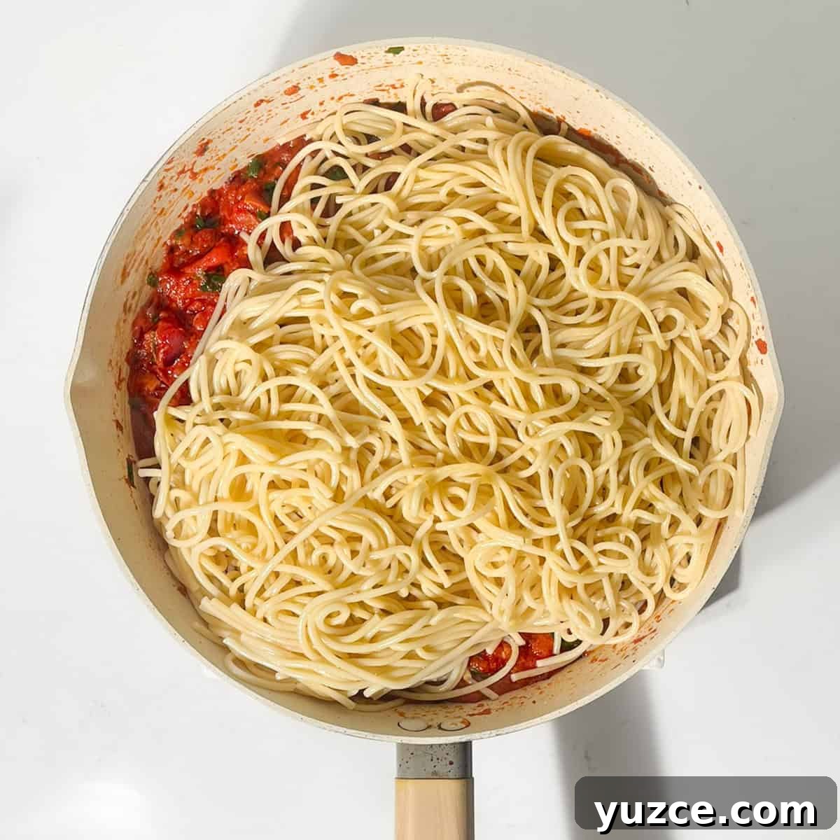 Spaghetti all’Arrabbiata Recipe: Spicy Tomato Pasta Guide 9 Adding the cooked spaghetti to the Arrabiata sauce in a large frying pan.