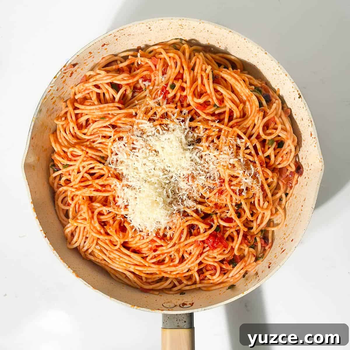 Spaghetti all’Arrabbiata Recipe: Spicy Tomato Pasta Guide 10 Spaghetti arrabiate in a frying pan with grated parmesan sprinkled on top.