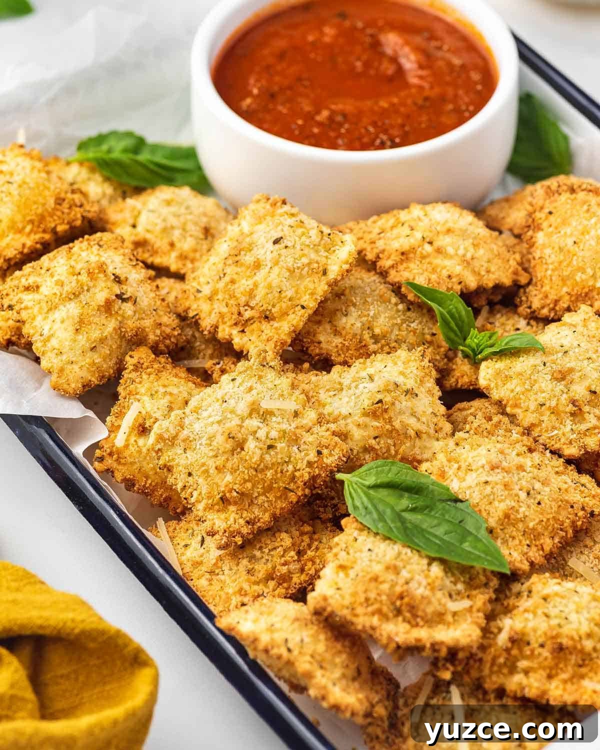 Crispy Air Fryer Ravioli: Quick Homemade Fried Dumplings 7 A tray of air fryer ravioli with a small bowl of marinara.