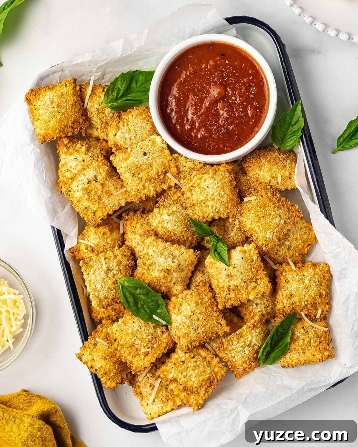 A tray of air fryer ravioli with a small bowl of dipping sauce on the side.