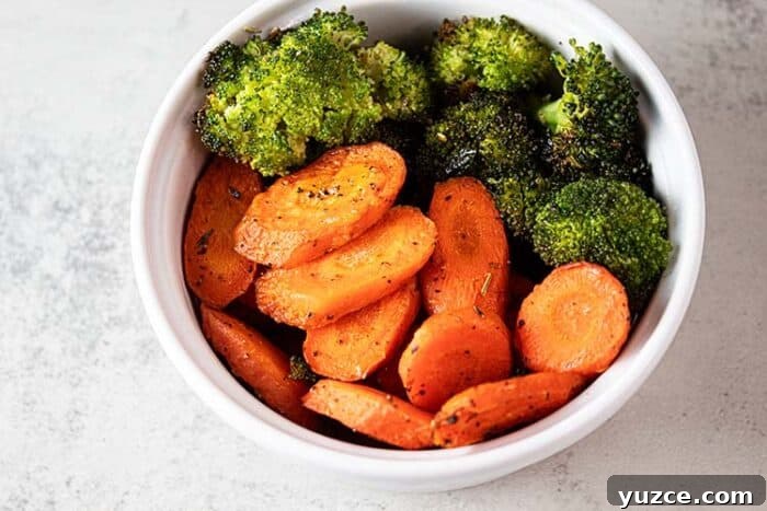 overhead view of oven roasted carrots and broccoli in white serving bowl