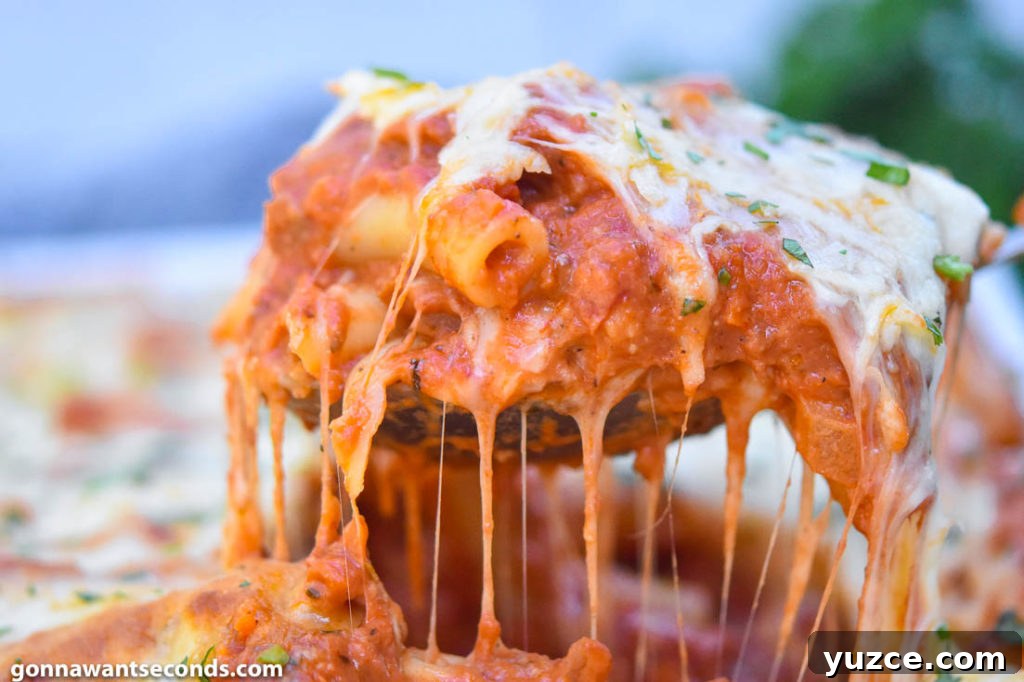 Tour the flavors of Italy with a ziti pasta recipe featuring plenty of creamy melted cheese, perfectly cooked ziti pasta and lots of fragrant herbs. #ZitiPasta #ZitiPastaRecipes wooden ladle scooping baked ziti with Italian sausage from the casserole dish