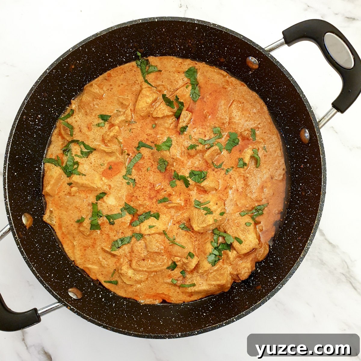 Creamy Murgh Makhani (Authentic Butter Chicken Recipe) 11 A frying pan of butter chicken garnished with chopped coriander.
