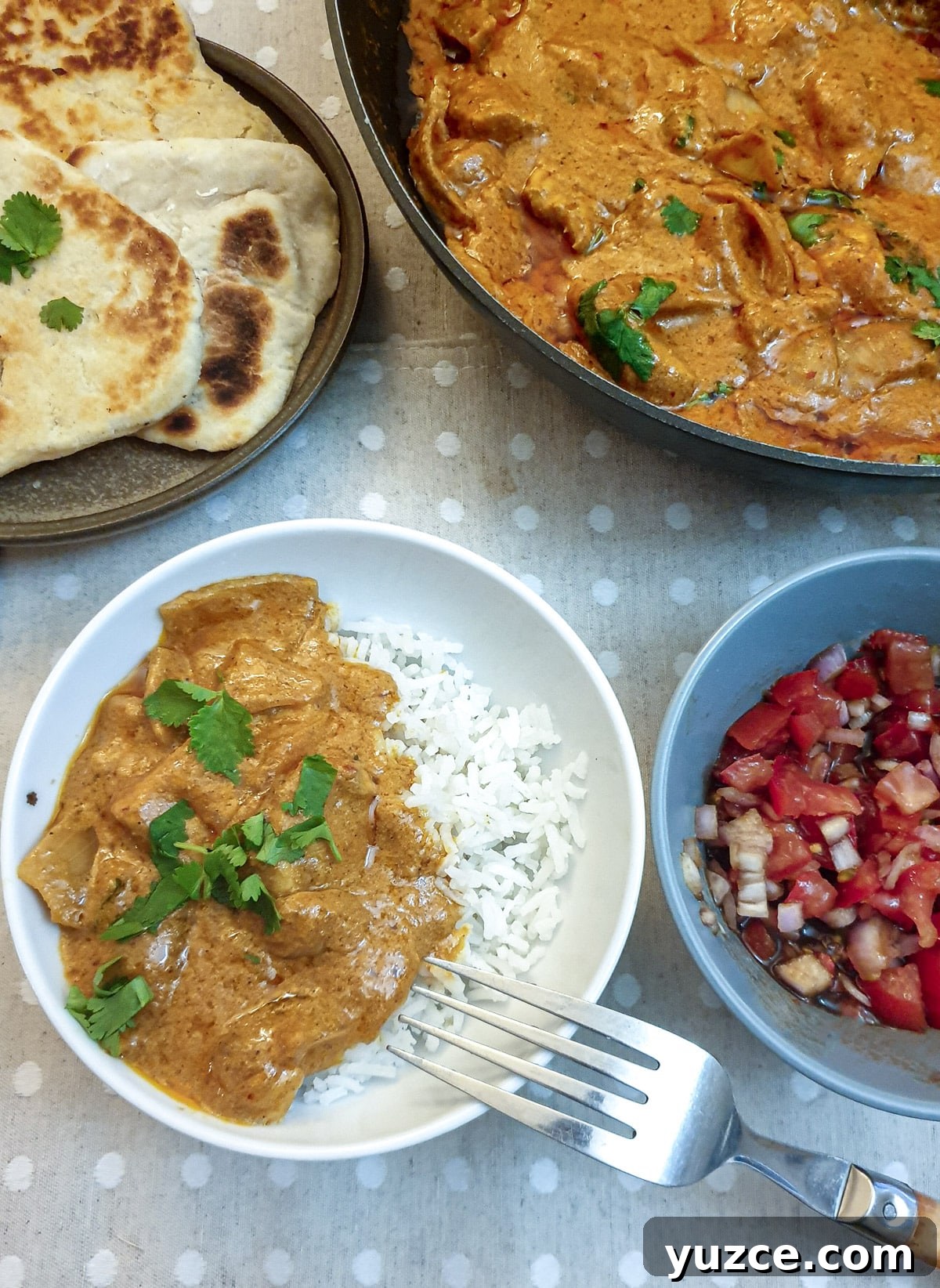 Creamy Murgh Makhani (Authentic Butter Chicken Recipe) 12 A white bowl containing rice and butter chicken alongside dishes containing tomato sambal and garlic naan bread.