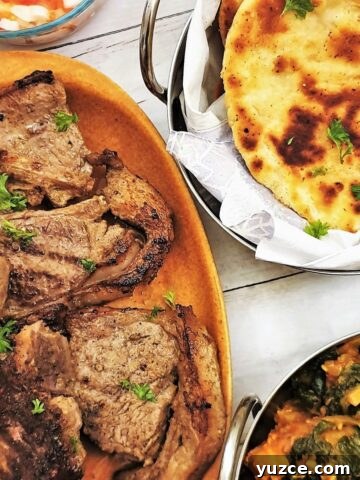 Tandori lamb chops on a plate with naan bread and saag aloo.