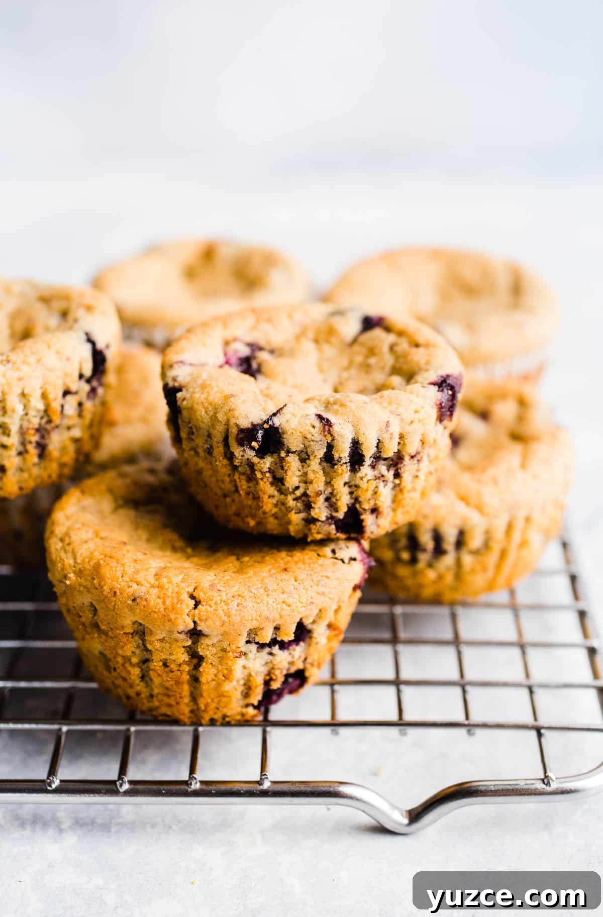 Blueberry muffins stacked two by two on a wire rack.