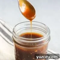 Teriyaki sauce dripping from a spoon over a mason jar filled with teriyaki.