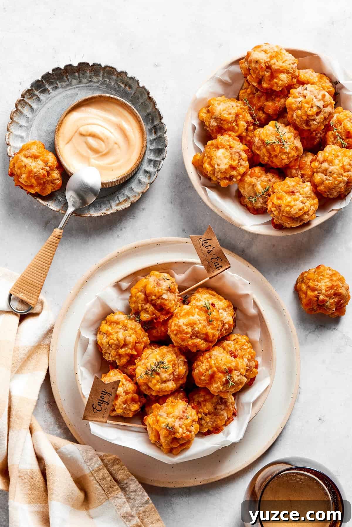 Two bowls of sausage balls and a bowl of dip and a spoon.