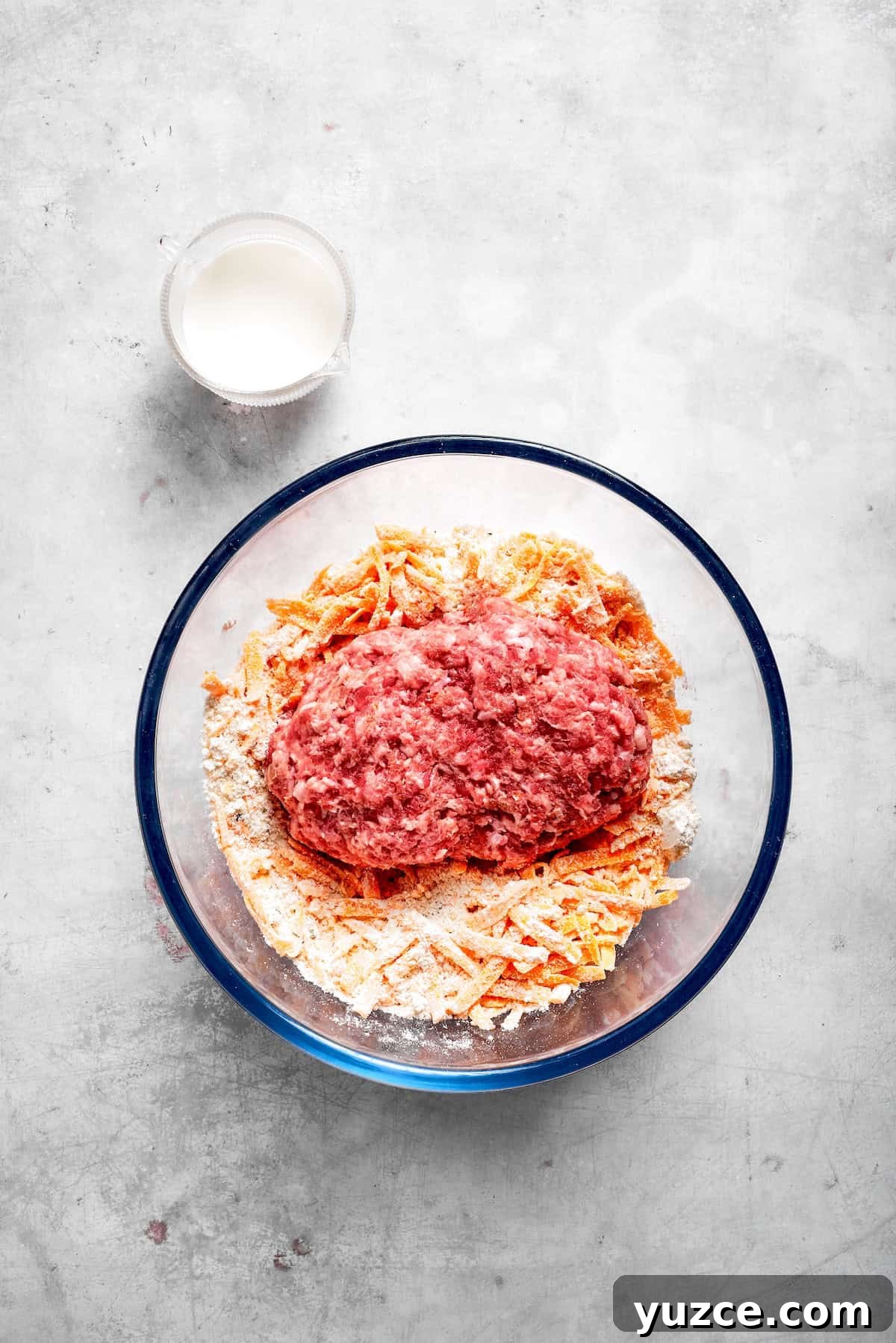 The ingredients for sausage balls placed in a glass bowl.