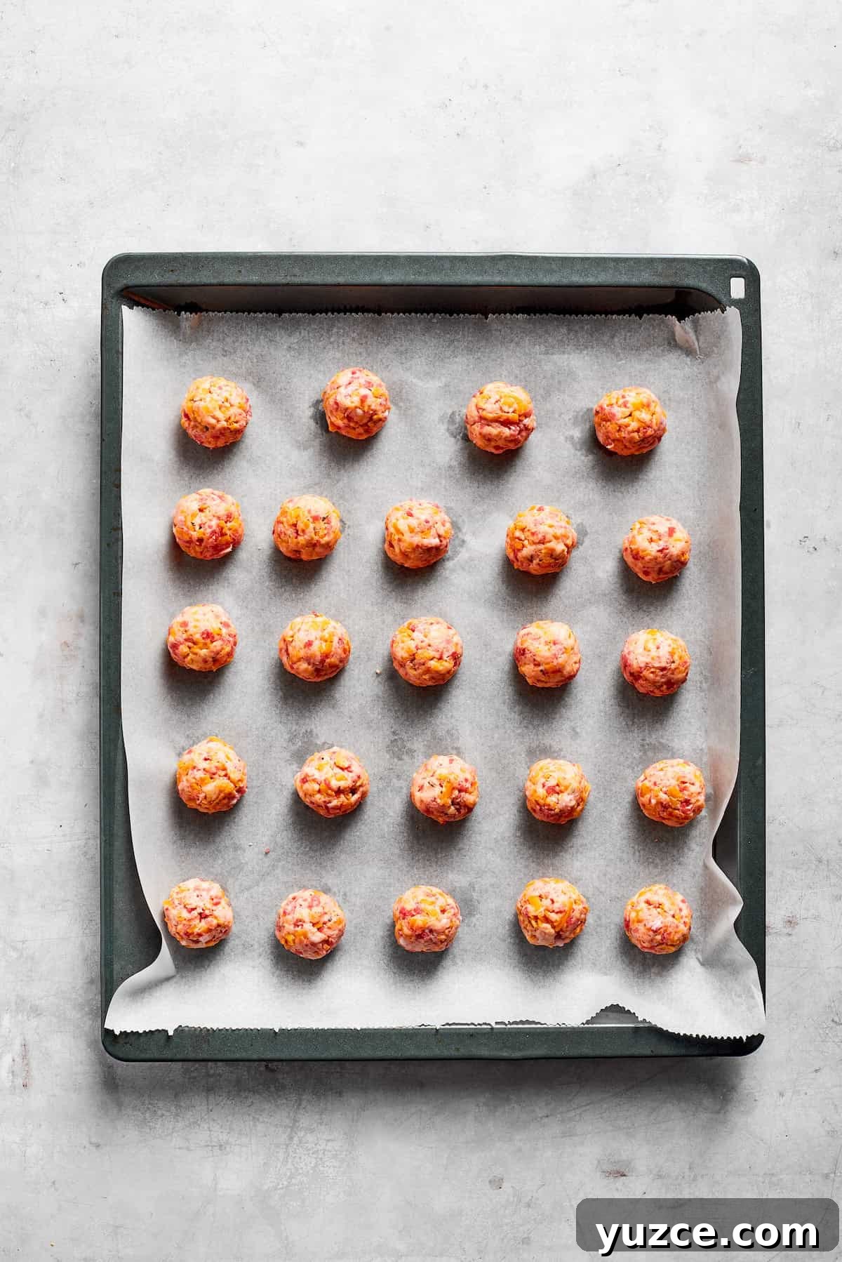 A lined baking tray with sausage balls.
