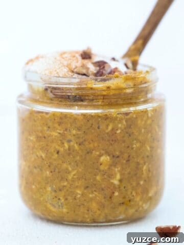 Pumpkin Spice Overnight Oats in a jar topped with whipped cream and pecans.