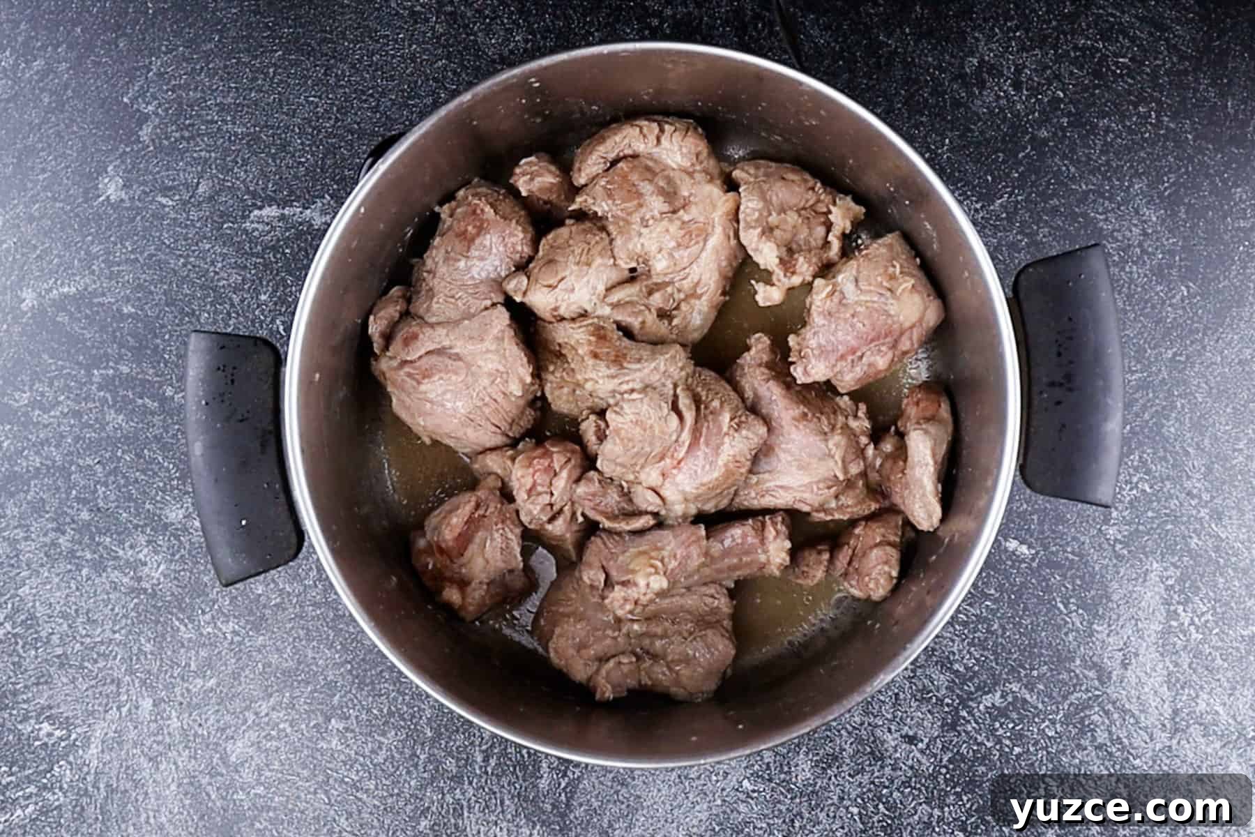 Authentic Pork Carnitas Street Tacos Recipe 6 Browned pork butt pieces in pot.