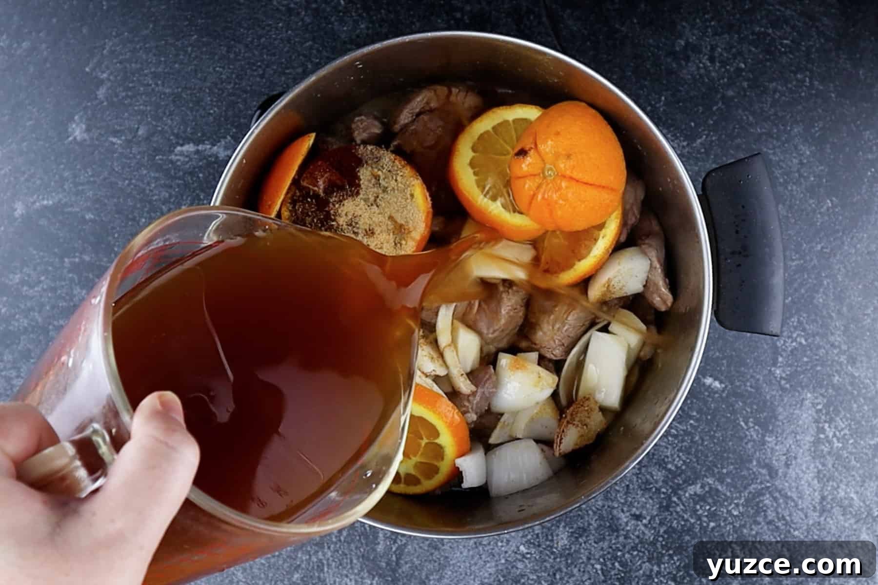 Authentic Pork Carnitas Street Tacos Recipe 7 Adding broth to the cooking pot with pork butt, spices, orange, and onion.